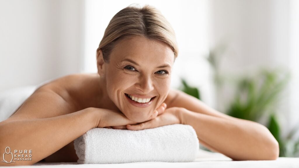 A mother enjoying a relaxing Swedish massage at home in a softly lit bedroom, surrounded by spring flowers, candles, and calming decor, capturing the peaceful essence of an in-home spa experience.
